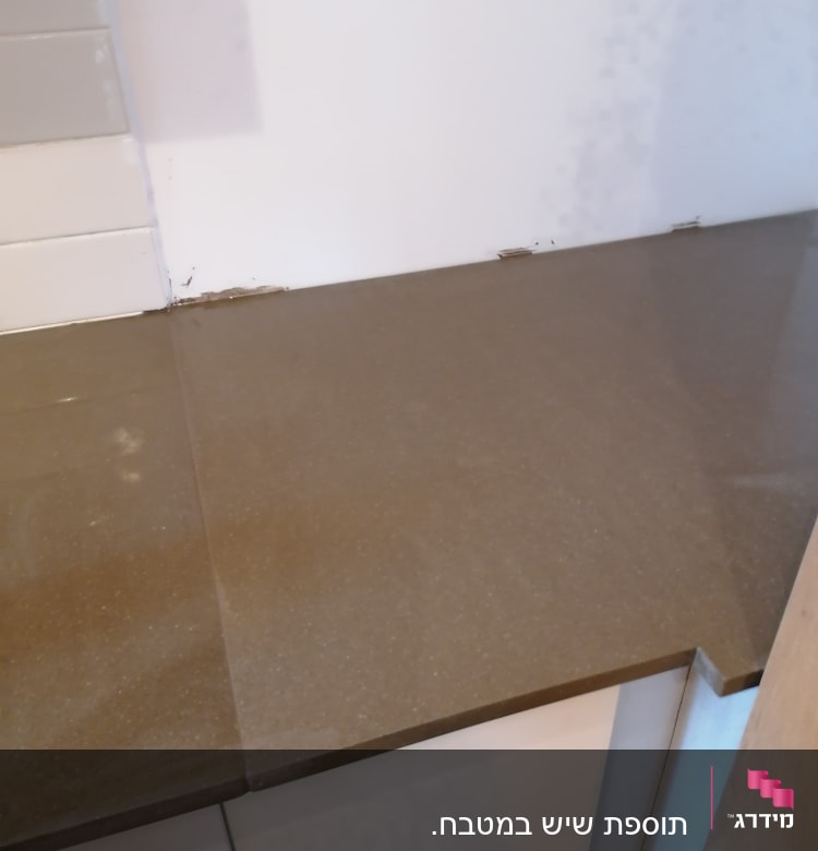 משטח שיש חום במטבח עם קיר לבן